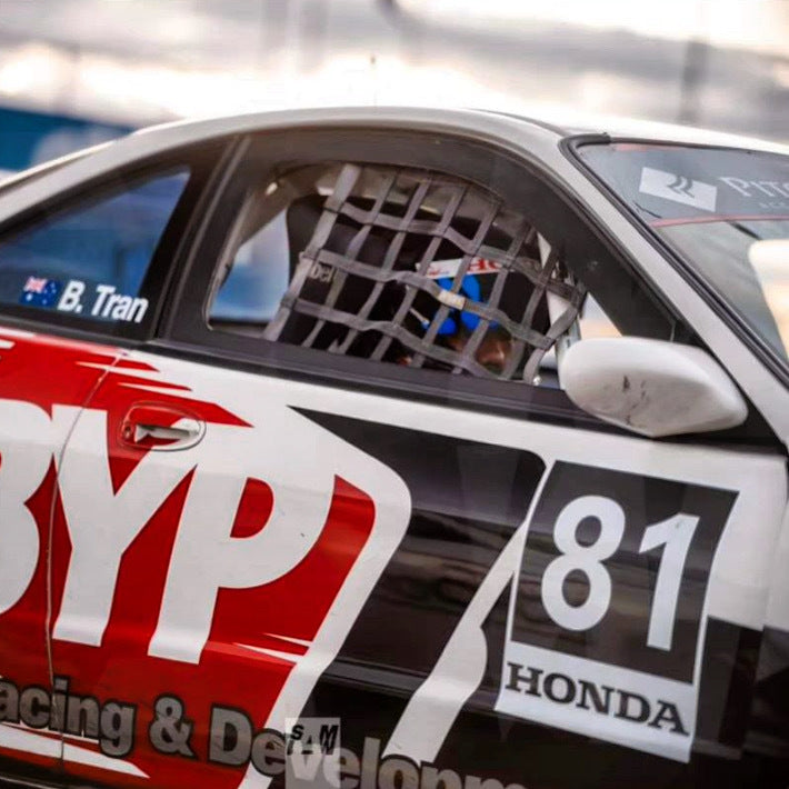Racing car with 'BYP Racing & Development' and 'Honda' branding, driver visible through a cage.